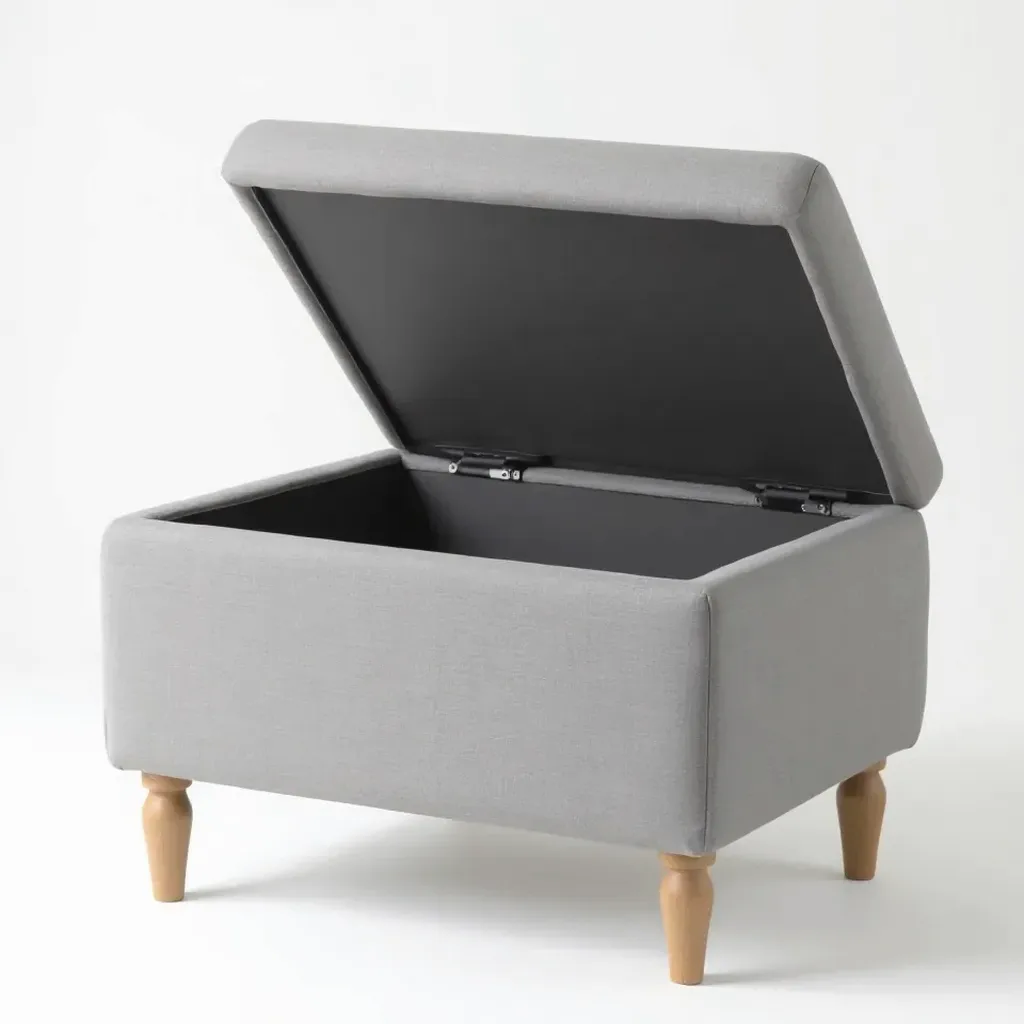 Upholstered grey linen storage ottoman from three-quarter view with lid open revealing storage interior, birch wooden legs visible
